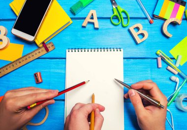 Okul kavramı, takım çalışması. Kurşun kalem ve tükenmez kalem ile üç el bir defter ile masaüstü mavi ahşap arka plan üzerinde beyaz sayfalar üzerine gelin. Yaratıcı bozukluk. İnsanlar yeni fikirler, ortak proje geliştirmek. Eğitim.