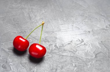 iki taze Olgun kırmızı kiraz gri beton zemin, yaz berry. minimalizm. metin için yer