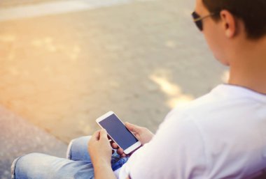 adam bir hareket eden smartphone tutarak ve ekrana bakarak. telefon bağımlılığı, sosyal ağlar. Internet üzerinde çalışma. mesajı yazın. güneşli bir gün. yakın çekim, metin için yer