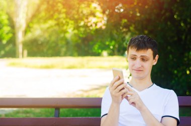 Genç bir Avrupa adam bir şehir parkta bir bankta oturur ve seyir telefon komik bir surat yapar. Aşırı sürpriz ve iğrenme, aniden kavramı. Beklenmedik Haberler, aniden.