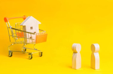 İnsanlar bir süpermarket sepetten ahşap bir evde arka plan üzerinde stand. Emlak kavramı. Satın alma, satış ve bir ev kiralama. Kredi bir daireye, ipotek oranı için. Genç aileler için uygun fiyatlı konut.