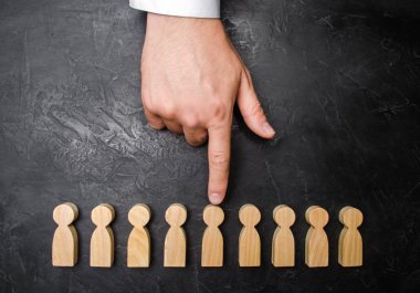 Bir işadamı el ahşap bir insan figürü için işaret eder. İşçiler, aratmak insan kaynakları yönetimi kavramı. İşe alma ve volnenie çalışanları, basınç, işçi hakları ihlali.