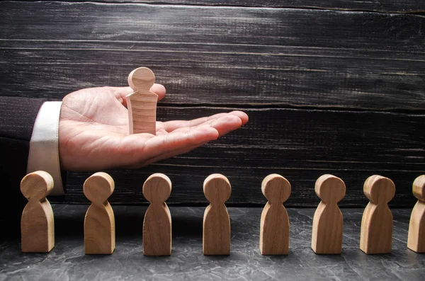 Bir işadamı bir ahşap lider figürü diğer işçiler, bir dizi üzerinden elini avuç içinde tutar. Kavramı lider, takım çalışması. İş ve departman yönetimi. Büyük patron. Promosyon. Kariyer.