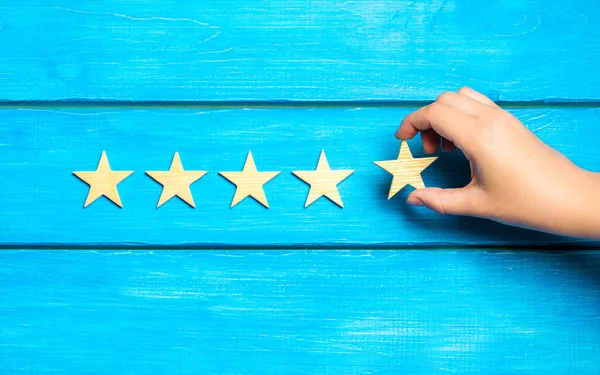 hand puts the fifth star. Quality status is five stars. A new star, achievement, universal recognition.The critic determines the rating of the restaurant, hotel, institution. Quality mark.