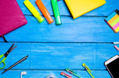 İşyeri mavi ahşap bir masa üzerinde okul öğrencisi. Yaratıcı bozukluğu, dağınık kalem, kalem. Metin, yer kimse. Eğitim, okul malzemeleri kavramı. Smartphone