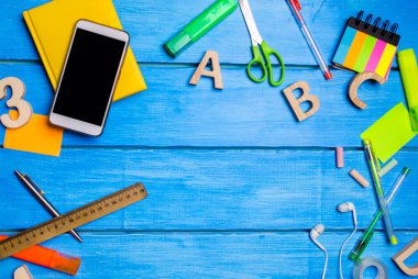 İşyeri mavi ahşap bir masa üzerinde okul öğrencisi. Yaratıcı bozukluğu, dağınık kalem, kalem. Metin, yer kimse. Eğitim, okul malzemeleri kavramı. Smartphone