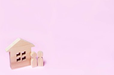 Bir çift pembe bir arka plan üzerinde bir ev yakın duruyor. Sevgi ve sadakat, ev konfor kavramını. Satın alma ve Emlak satış. Genç aileler için uygun fiyatlı konut. Emlakçılar.