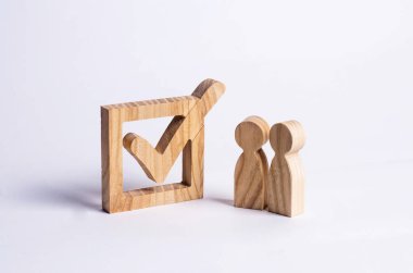 İki ahşap insan figürleri birlikte bir onay kutusunun yanındaki bekletin. Seçimler ve sosyal teknolojileri kavramı. Gönüllüler, partiler, adaylar, seçim electorates. İnsan hakları.