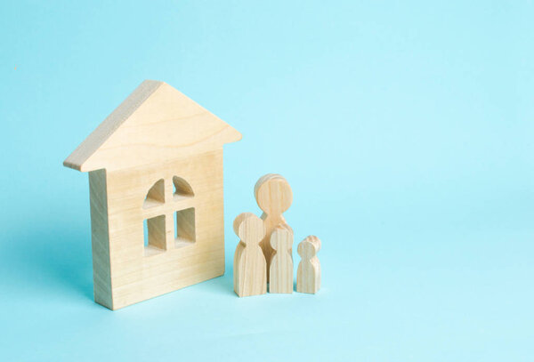 Family is standing near the house. Wooden figures of persons stand near a wooden house. The concept of a couple in love, cohabitants, parents, buyers and sellers at home. They live in the house