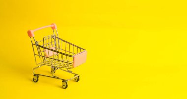 Süpermarket arabası sarı bir arka plan üzerinde duruyor. Alışveriş ve pazarlama, ticaret ve ticaret kavramı. İnsanların satın alma ruh. İstatistiksel veri, ticaret dengesi.