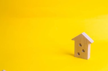 Sarı bir arka plan üzerinde bir çok katlı ev ahşap figürü. Üç katlı ev. Alış ve satış Emlak, inşaat. Daire ve daire. Minimalizm. sunumlar için.