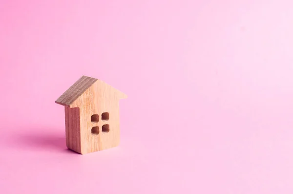 ピンクの背景の上に小さな木の家が立っています 不動産を売買することの概念を借りるします 家を探す現実的なハウジング 信用および貸付け金 事業への投資 — ストック写真