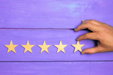 A woman's hand puts the fifth star. Quality status is five stars. A new star, achievement, universal recognition.The critic determines the rating of the restaurant, hotel, institution. Quality mark. clipart