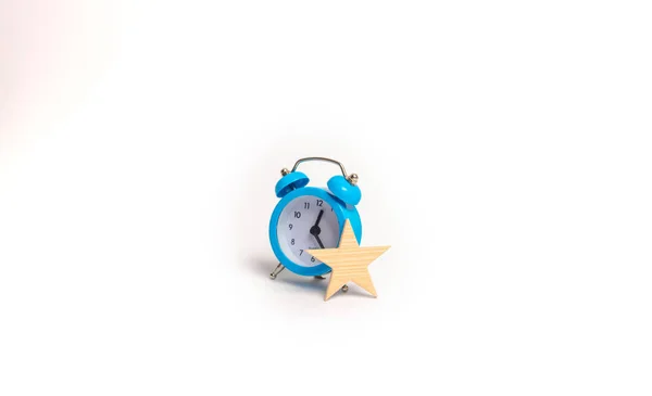 A blue alarm clock and a star. Concept vip. Additional time, privileges. Special offer, limited series. Exclusivity. Time is money. Minimalism and abstractionism. Business.