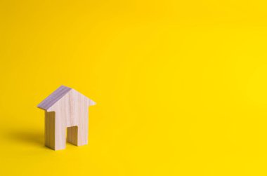 Küçük bir ahşap ev sarı bir arka plan üzerinde duruyor. Alış ve satış Emlak, kavramı kiralama. Bir ev için arama. Uygun fiyatlı konut, kredi ve kredi. İş yatırımları