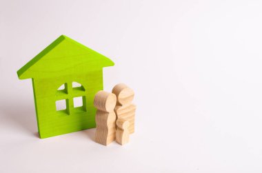 Beyaz zemin üzerinde bir ahşap evin yakınındaki insanlar rakamlar hazır. Genç bir aile evlerinin duruyor. Bir ev satın alma kavramı. Özellik. Aile mutluluğu. Toplum birimi.