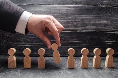 Elini bir işadamı bir adam ahşap bir rakam tutuyor. İşe alma ve işçiler, promosyon ateş arama kavramı. İş taktik ve strateji, yönetim, işletme yönetimi.