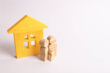 Beyaz zemin üzerinde bir ahşap evin yakınındaki insanlar rakamlar hazır. Genç bir aile evlerinin duruyor. Bir ev satın alma kavramı. Özellik. Aile mutluluğu. Toplum birimi.