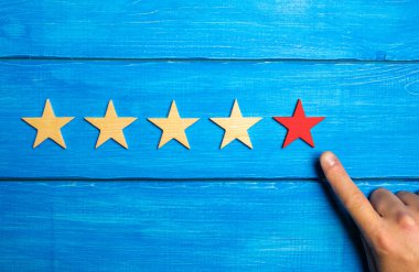 Erkek el beşinci Kızılyıldız mavi ahşap arka plan üzerinde işaret eder. Beş yıldız. Restoran ya da otel, uygulama puan verin. Kalite ve hizmeti, kritik değerlendirme değerlendirilmesi.