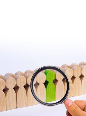 Seçilmiş kişi diğerleri arasında. Yeşil renk bir insan figürü kalabalığın içinde duruyor. Ahşap figürler insan. Yetenekli bir işçi, başarılı bir seçim. Promosyon. Çalışan için arama kavramı.