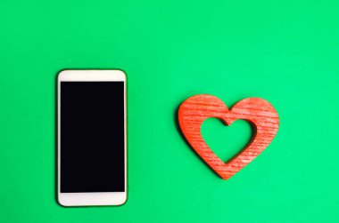 bağımlılık sosyal ağlarda. telefon smartphone ve kalp yeşil bir arka plan üzerinde. Online dating, flört, mesaj ve senin aşk bir arama. aşk ve iletişim kavramı