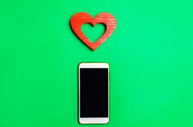 bağımlılık sosyal ağlarda. telefon smartphone ve kalp yeşil bir arka plan üzerinde. Online dating, flört, mesaj ve senin aşk bir arama. aşk ve iletişim kavramı
