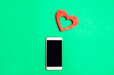 bağımlılık sosyal ağlarda. telefon smartphone ve kalp yeşil bir arka plan üzerinde. Online dating, flört, mesaj ve senin aşk bir arama. aşk ve iletişim kavramı