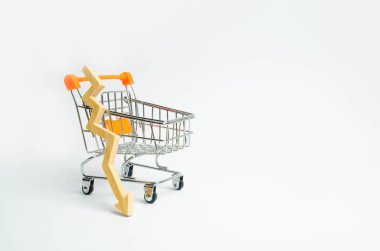 Bir süpermarket arabası ve beyaz bir arka plan aşağı ahşap bir oku. Prasada düşüşü ve tüketici duyarlılığı bozulma kavramı. Satın alma gücü içinde düşüş.