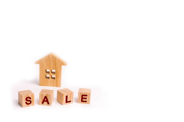 Wooden blocks with the word sale and wooden house on a white background. The concept of sales and seasonal sales of real estate and household goods. Discounts and promotions. Place for text.