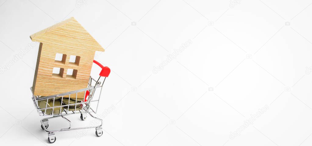 Property investment and house mortgage financial concept. buying, renting and selling apartments. real estate. Wooden house in a Supermarket trolley. credit, affordable housing for young families. banner. copy space
