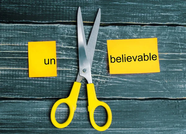 scissors cut the word unbelievable. concept believable. cuts the word \