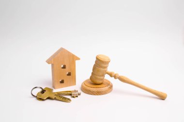 Wooden apartment house with keys and a judge hammer on a white background. The concept of the trial of an apartment house. Confiscation of property. Resettlement from emergency housing. clipart
