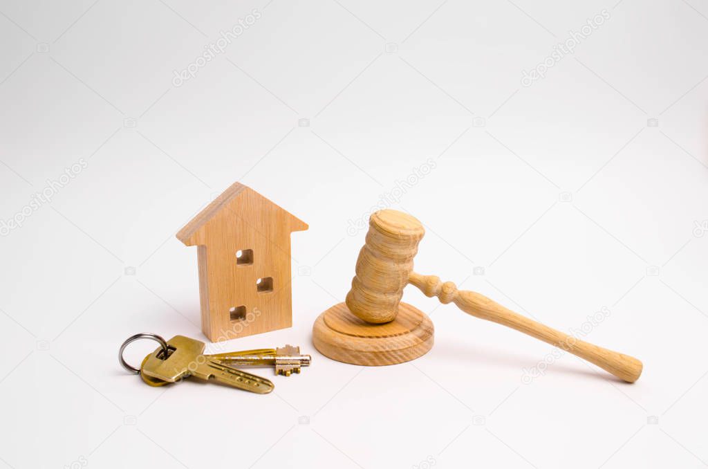 Wooden apartment house with keys and a judge hammer on a white background. The concept of the trial of an apartment house. Confiscation of property. Resettlement from emergency housing.