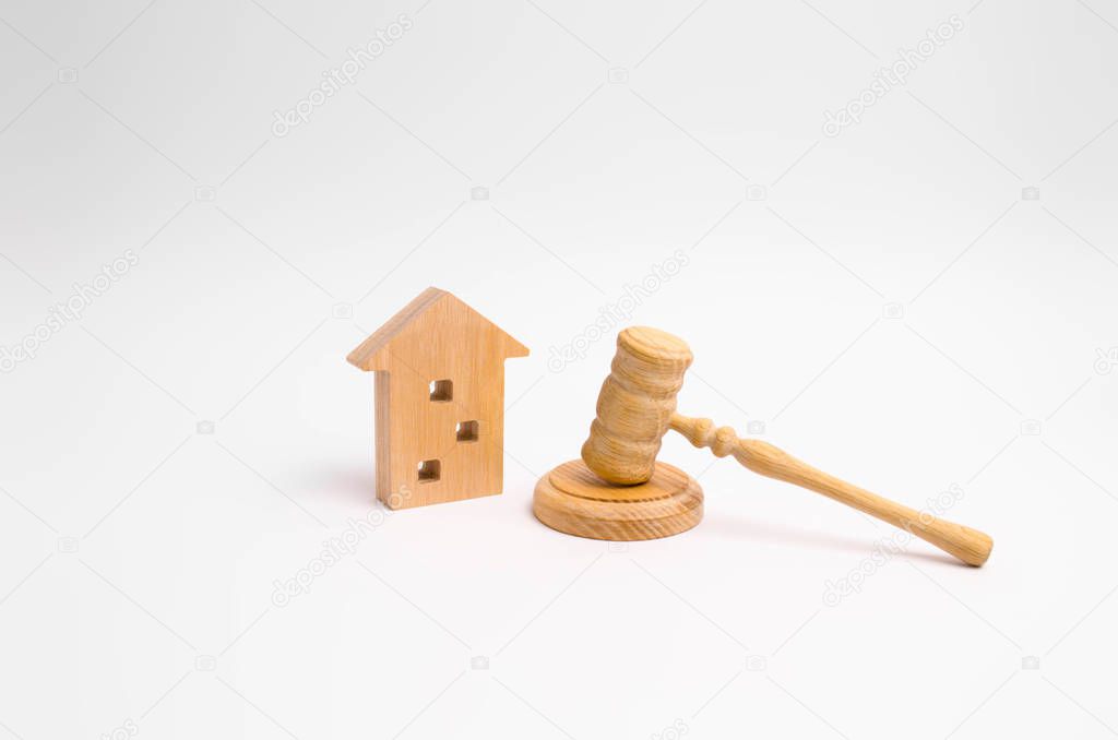 Wooden apartment house and hammer of the judge on a white background. The concept of the trial of an apartment building, the examination of cases between the tenants of the house.