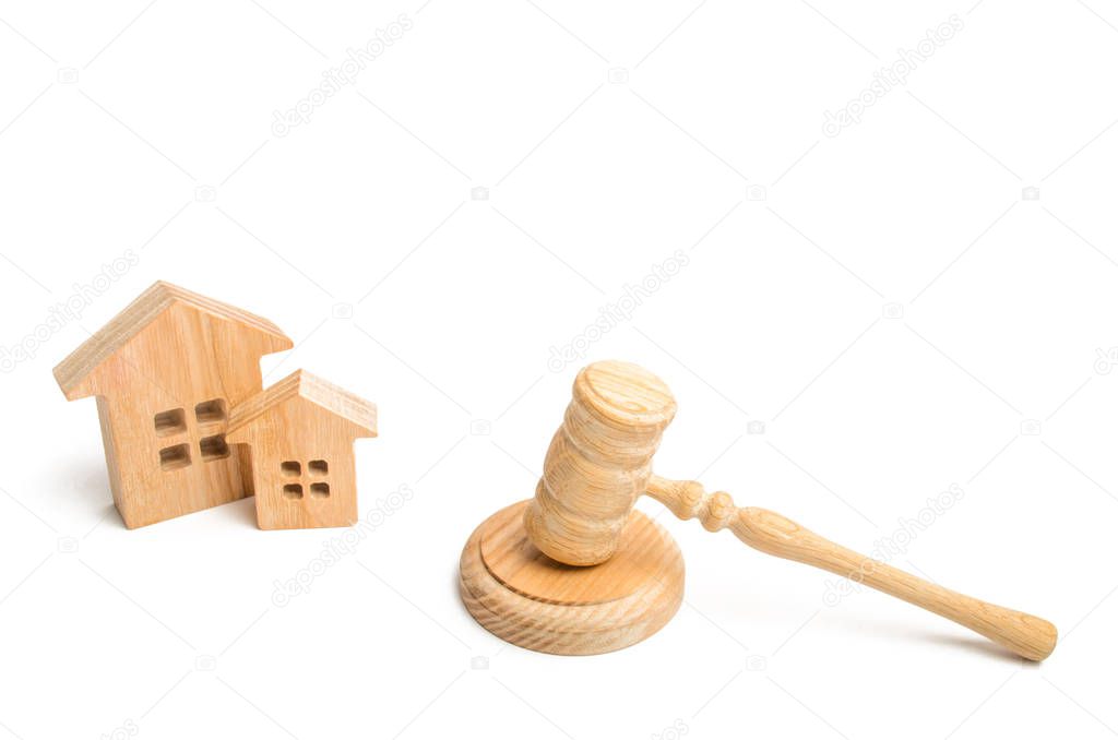 Two wooden houses and a hammer of the judge on a white background. court cases on property and real estate. Confiscation and nationalization, real estate scam. Issuance of permits for construction.