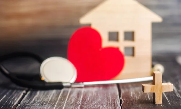 the concept of family medicine and insurance. stethoscope and heart on a black wooden background