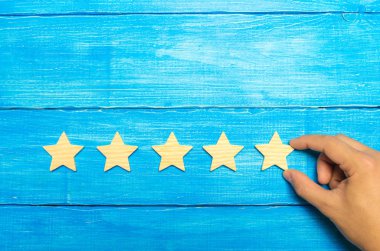 İşadamı'nın el takım elbiseli beşinci yıldız tutar. Beşinci yıldız almak. Oteller ve restoranlar ile ilgili değerlendirme, eleştirmenler ve ziyaretçiler değerlendirilmesi kavramı. Kalite düzeyi, iyi hizmet.