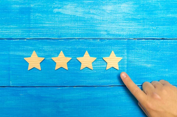 The businessman's hand in the suit points to the fourth star. Get the fifth star. The concept of the rating of hotels and restaurants, evaluation of critics and visitors. Quality level, good service.
