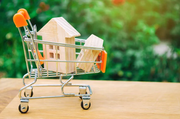 Property investment and house mortgage financial concept. buying, renting and selling apartments. real estate. Wooden house in a Supermarket trolley. credit, affordable housing for young families.