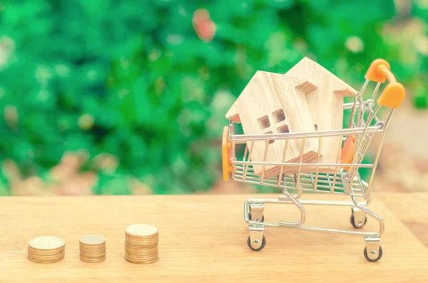 Wooden house in a Supermarket trolley. Property investment and house mortgage financial concept. buying, renting and selling apartments. real estate. saving money