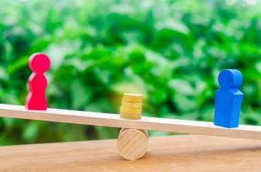 ahşap figürler bir erkek ve bir kadın stand üzerinde ölçekler ve paraları aralarında. cinsiyet ücret farkını kavramı. Gelir eşitsizliği. kadınların baskı. cinsiyet ayrımcılığı. denge