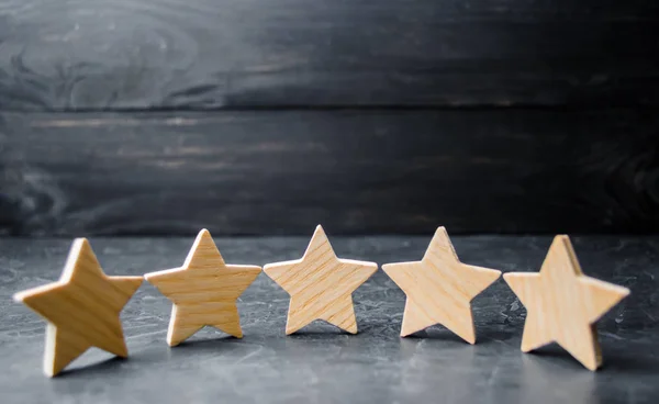 Five wooden stars. Get the fifth star. The concept of the rating of hotels and restaurants, the evaluation of critics and visitors. Quality level, good service. selective focus