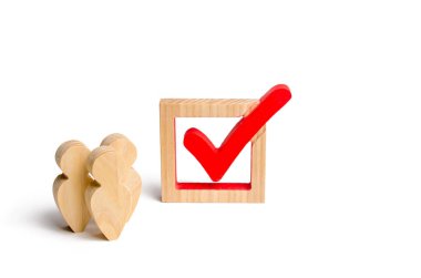 Üç ahşap insan figürleri birlikte kırmızı onay kutusunun yanındaki bekletin. Gönüllüler, partiler, adaylar, seçim electorates. İnsan hakları. Seçimler ve sosyal teknolojileri kavramı.