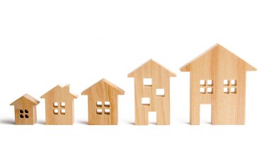 Wooden houses stand in ascending order on a white background. Isolate The concept of increasing population density and high-rise buildings. Agglomeration and urban growth. Selective focus clipart
