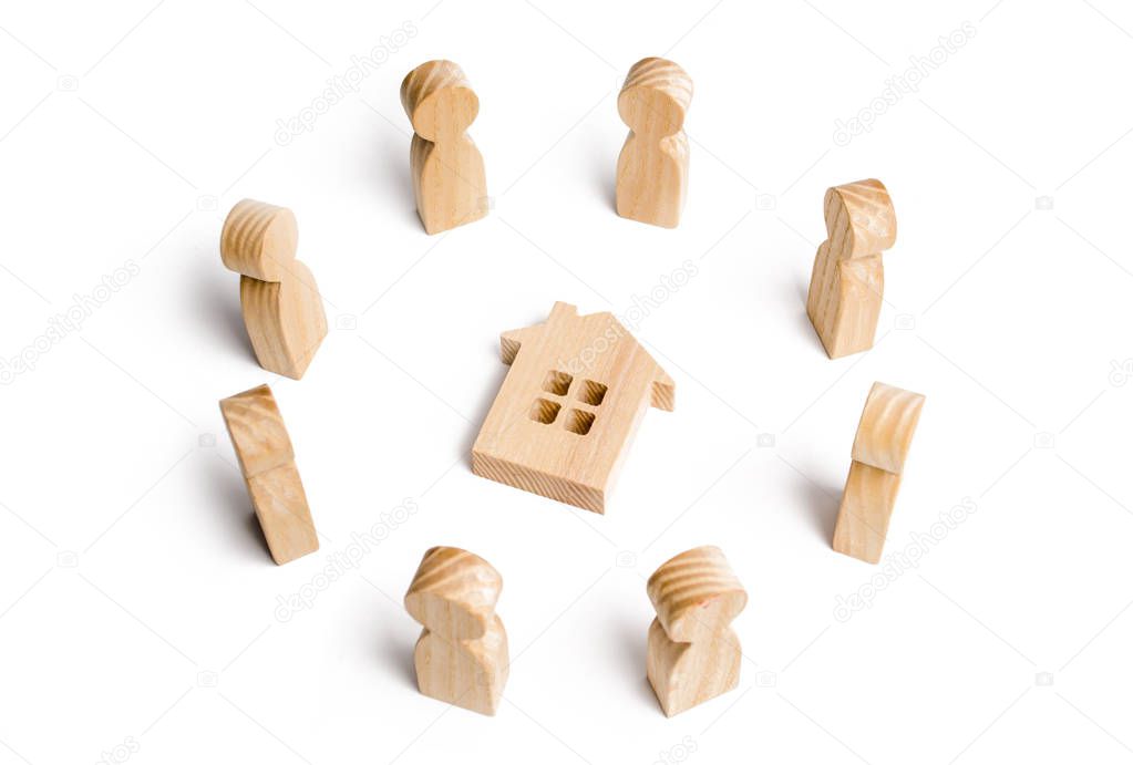 Wooden figurines of people stand around the house. Search for a new home and real estate. Buying or selling a home. Moving to a new home. Rent or construction. Buying a property. Investments