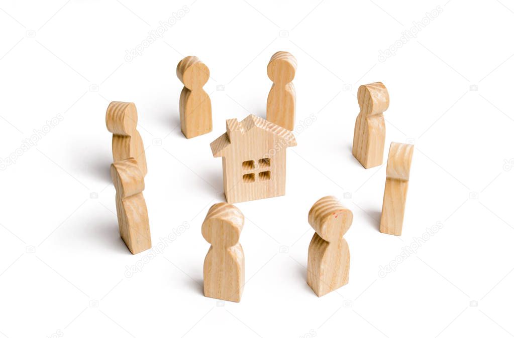 Wooden figurines of people stand around the house. Search for a new home and real estate. Buying or selling a home. Moving to a new home. Rent or construction. Buying a property. Investments