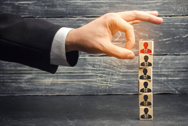 the businessman removes / dismisses the employee from the team. management within the team. wooden blocks with a picture of workers. control arm. leader. resignation