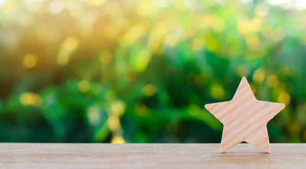 One wooden star. Rating hotel, restaurant, hotel. Overview. appreciation of the critic. Negative feedback. poor quality of service. green bokeh background. selective focus