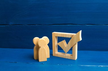 Gönüllüler, partiler, adaylar, seçim electorates. Seçici odak üç ahşap insan figürleri birlikte bir onay kutusunun yanındaki bekletin. Seçimler ve sosyal teknolojileri kavramı.