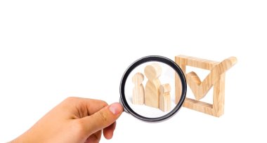 Büyüteç Camı birlikte bir onay kutusunda yanındaki üç ahşap insan figürleri standında arıyor. Seçimler ve sosyal teknolojileri kavramı. Gönüllüler, partiler, adaylar. İnsan hakları